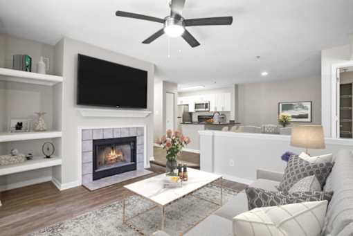 Renovated living area with a fireplace and ceiling fan at The Crossings at Russett in Laurel, MD