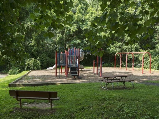 Playground surrounded by lush green landscaping at Trillium Apartments, Fairfax, 22031