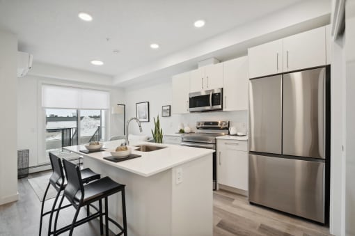 an open kitchen with a large island and stainless steel refrigerator