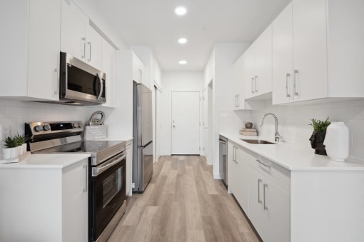 a white kitchen with white cabinets and stainless steel appliances