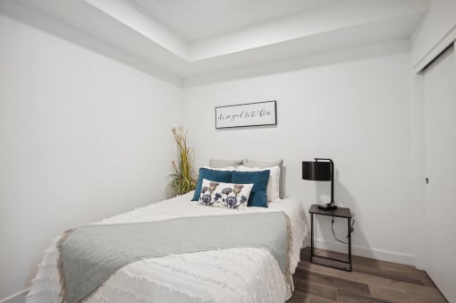 a bedroom with white walls and a bed with blue and white pillows