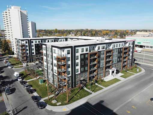 A large apartment complex with a parking lot in front.