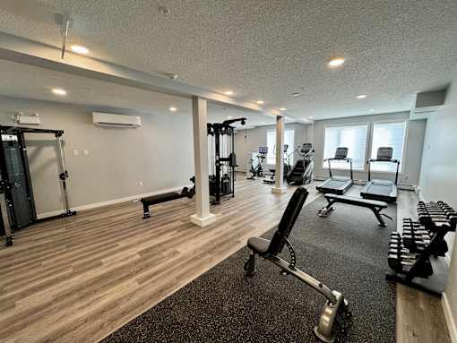 a gym with chairs and weights on the floor and windows