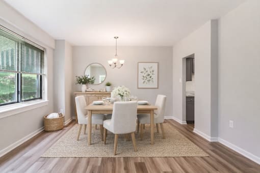 A dining room with a round mirror, a chandelier, and a framed picture on the wall.