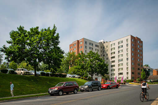 A cyclist rides down a street in front of a large apartment building.