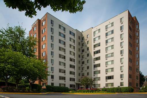 A large building with a red brick section and white sections with windows.