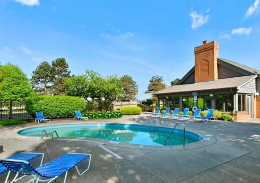 a swimming pool with blue chairs in front of a house