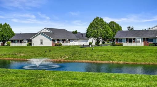 a fountain in a pond in front of a house