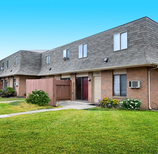 the front of a brick house with a yard and grass