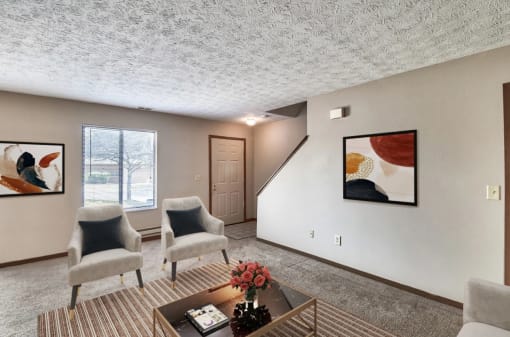 a living room with two chairs and a coffee table    and a staircase