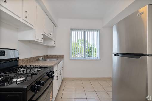 A kitchen with a black stove top and a stainless steel refrigerator.