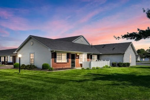 a house with a yard and a sunset in the background