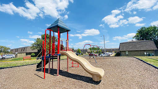 A playground with a red and blue structure and a yellow slide.