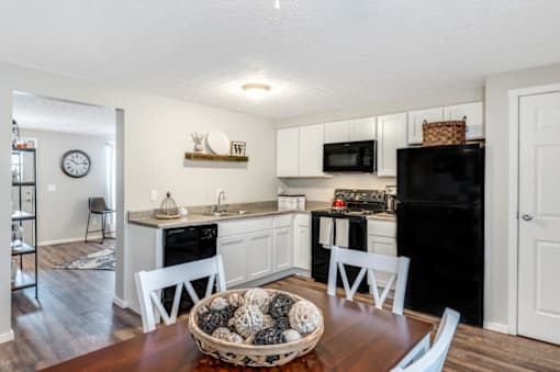 A kitchen with white cabinets and a black refrigerator.