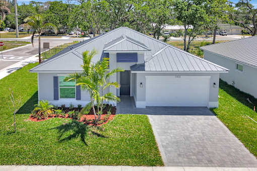 a white house with a driveway and a palm tree in front