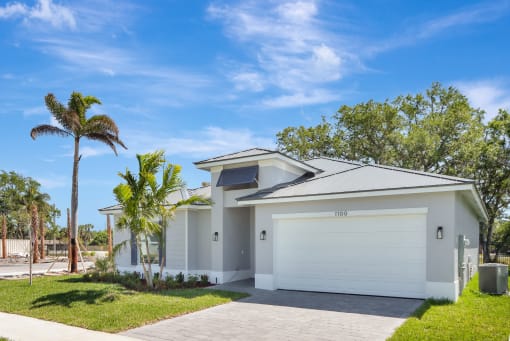 a white house with a garage and palm tree
