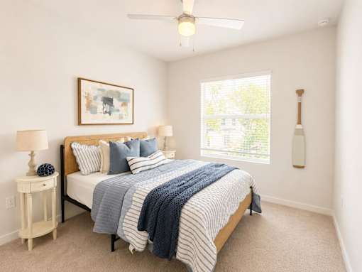 A bedroom with a bed, nightstand, and window.