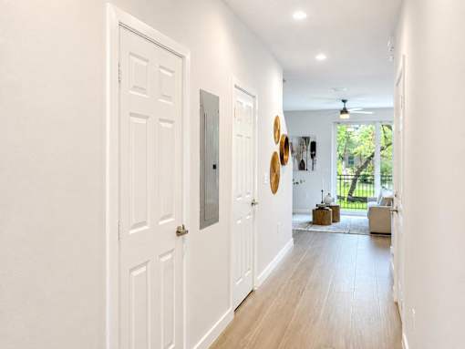 A hallway with white doors and a ceiling fan.