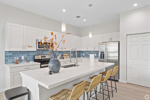 a kitchen with white cabinets and a large island with a white counter top
