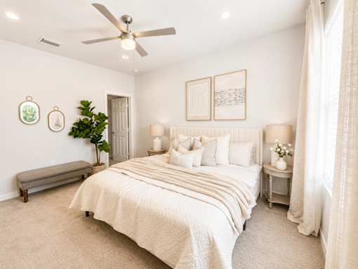 A bedroom with a large bed and a ceiling fan.