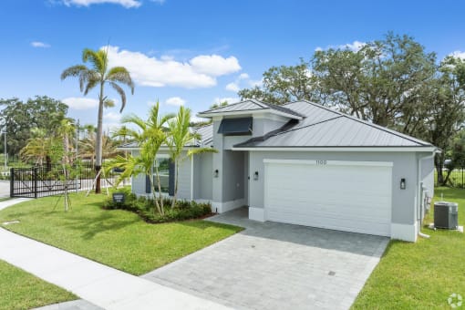 a home with a white garage and a lawn with palm trees