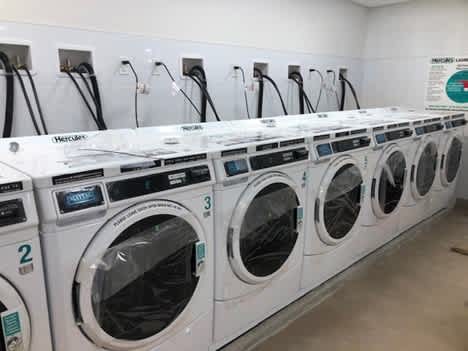 A row of Mercedes washing machines are lined up in a laundromat.