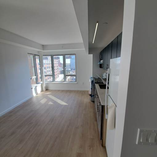 A kitchen with wooden floors and a window overlooking the city.