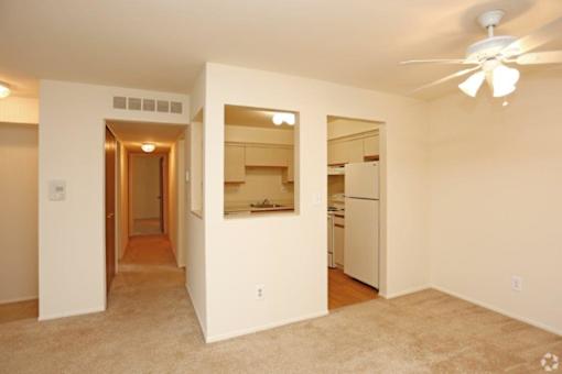 an empty living room and kitchen with a ceiling fan