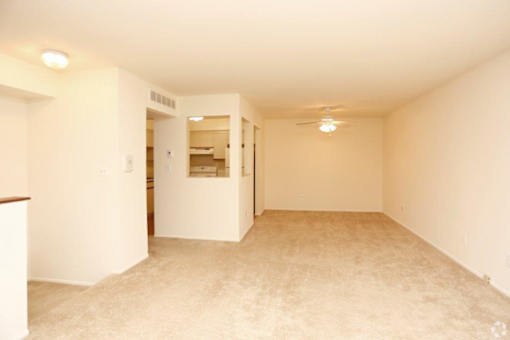an empty living room with a ceiling fan and a closet