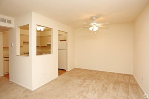 an empty living room with a ceiling fan