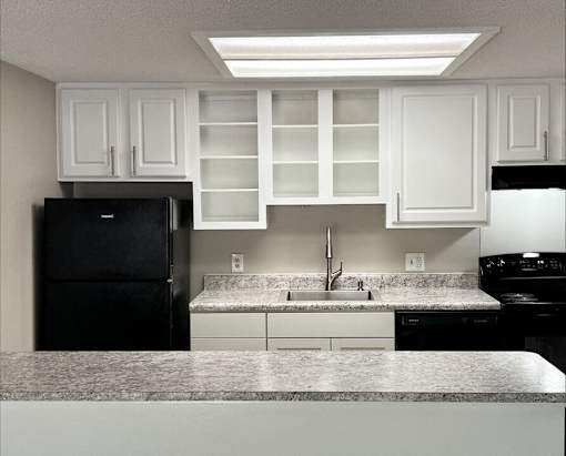 A kitchen with black appliances and white cabinets