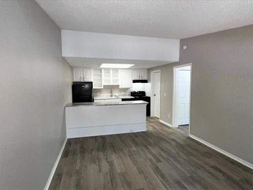 A kitchen with a black fridge, white cabinets, and a white island