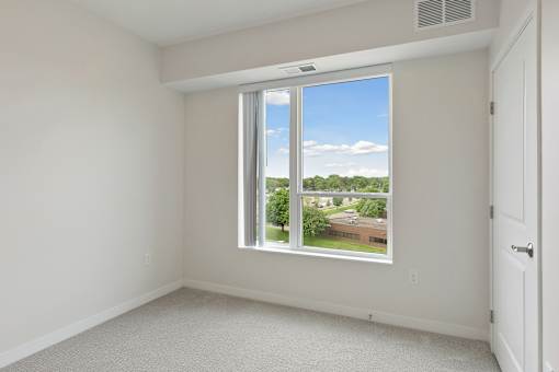 A room with a large window overlooking a residential area at Sonder Point 50+ Apartments, Brooklyn Center, 55430
