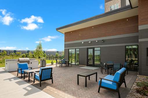 A patio with blue chairs and a table outside a building.