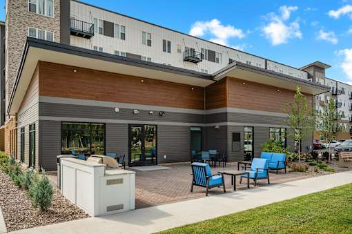 A modern building with a wooden facade and blue chairs in front.