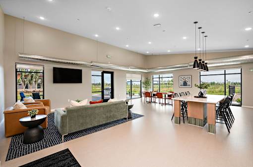 A spacious living room with a large couch, a television, and a dining area with chairs and a table.