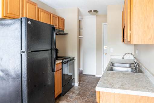 a kitchen with black appliances and wooden cabinets at Northtown Village Apartments, Minnesota
