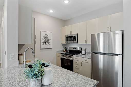A kitchen with a stainless steel refrigerator, microwave, and oven.