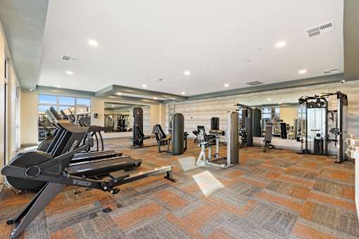 A gym with a variety of equipment including treadmills, weights, and exercise machines at Agave House Apartments, Arizona