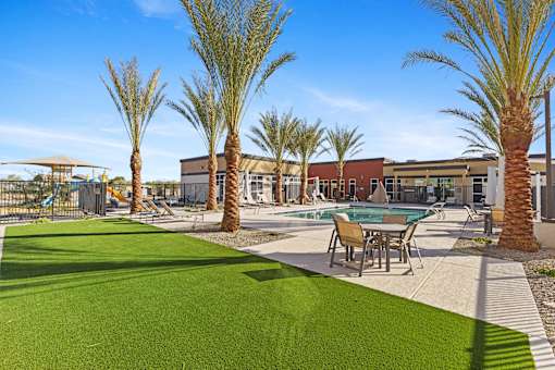 A pool surrounded by palm trees and a green lawn at Agave House Apartments, Casa Grande