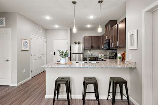 A kitchen with a granite countertop and bar stools.at Decatur Landing I & II, Brooklyn Park, 55445