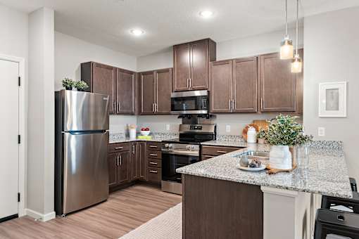 A kitchen with brown cabinets and a stainless steel refrigerator.at Decatur Landing I & II, Brooklyn Park, MN 55445