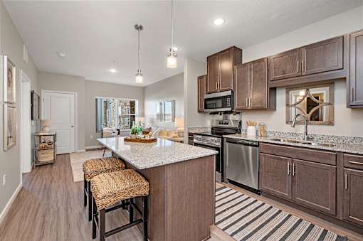 A kitchen with brown cabinets and a white island.at Decatur Landing I & II, Brooklyn Park Minnesota