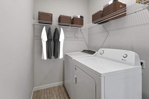 a white washer and dryer in a laundry room with a rack of clothes at EastGate Apartments, Rochester, Minnesota