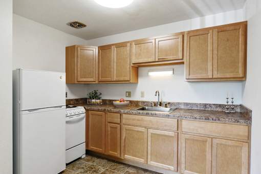 a kitchen with wooden cabinets and a white refrigerator at Humboldt Senior 55+ Apartments, Saint Paul, MN