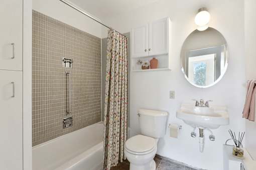 a white bathroom with a shower and a toilet and a sink at Humboldt Senior 55+ Apartments, Minnesota