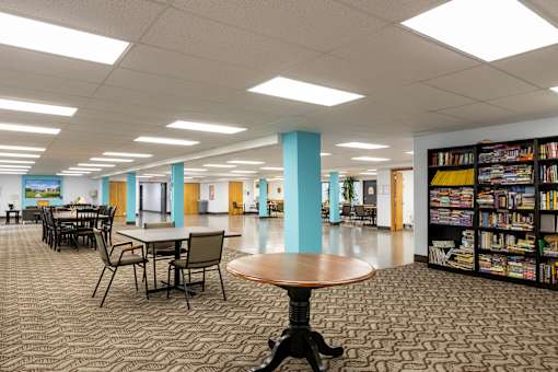 a large library with tables and chairs and bookshelves at Humboldt Senior 55+ Apartments, Saint Paul, MN, 55107