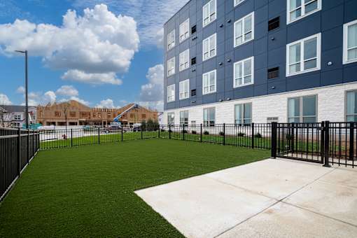 the yard of an apartment building with a green lawn and a fence at The Landing at Amber Fields Apartments, Rosemount