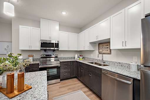 a kitchen with white cabinets and granite counter tops and stainless steel appliances at The Landing at Amber Fields Apartments, Rosemount, MN