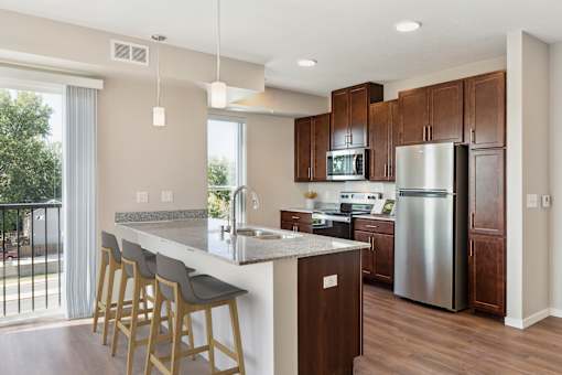a kitchen with a large island and stainless steel refrigerator at The Quill 55+ Apartments, Hastings, MN
